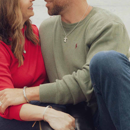 Man wearing Accord Cross necklace handcrafted in antiqued sterling silver with the pendant strung on your choice of chain along with his girlfriend and other sterling silver jewelry