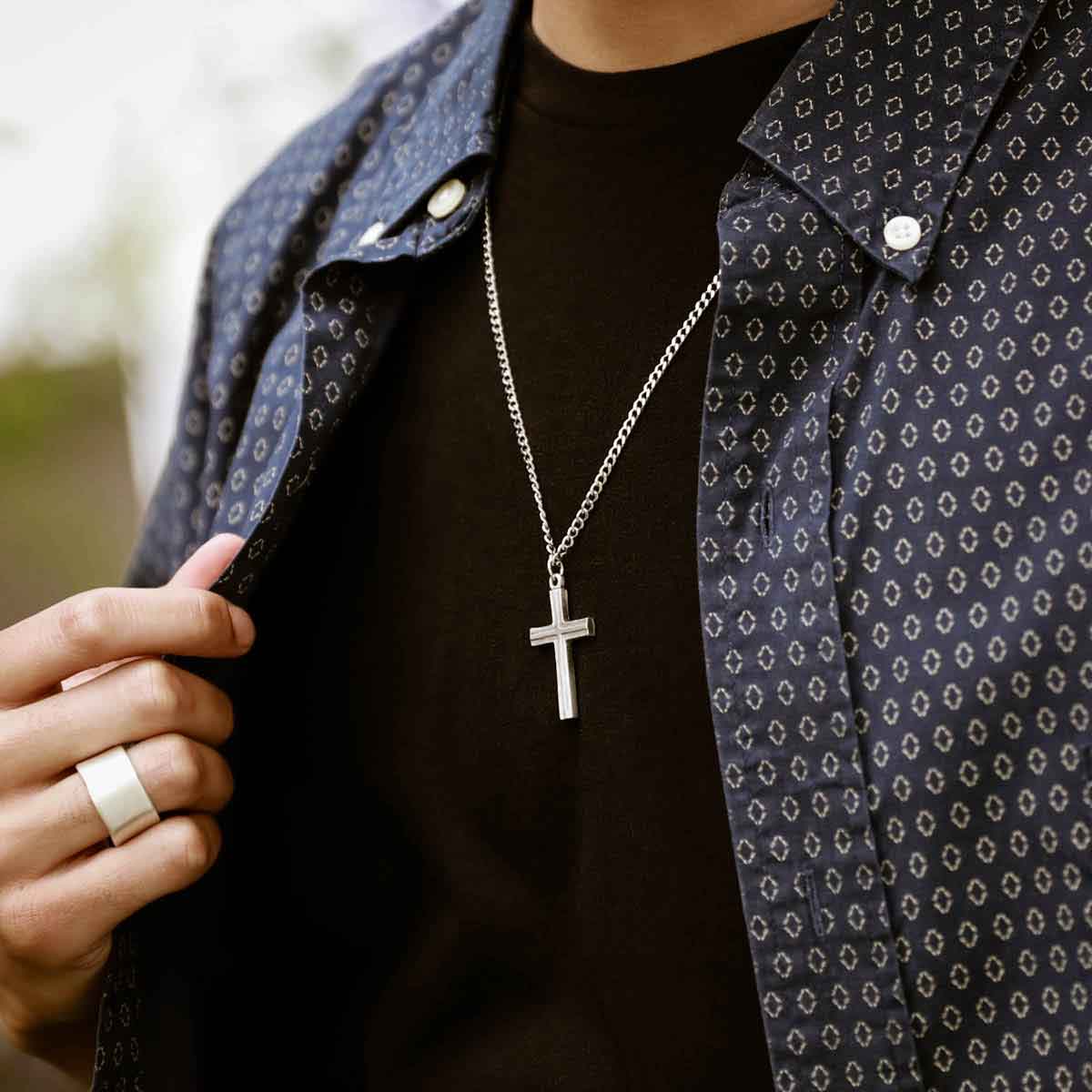 hand holding a pewter Adopted Cross Necklace