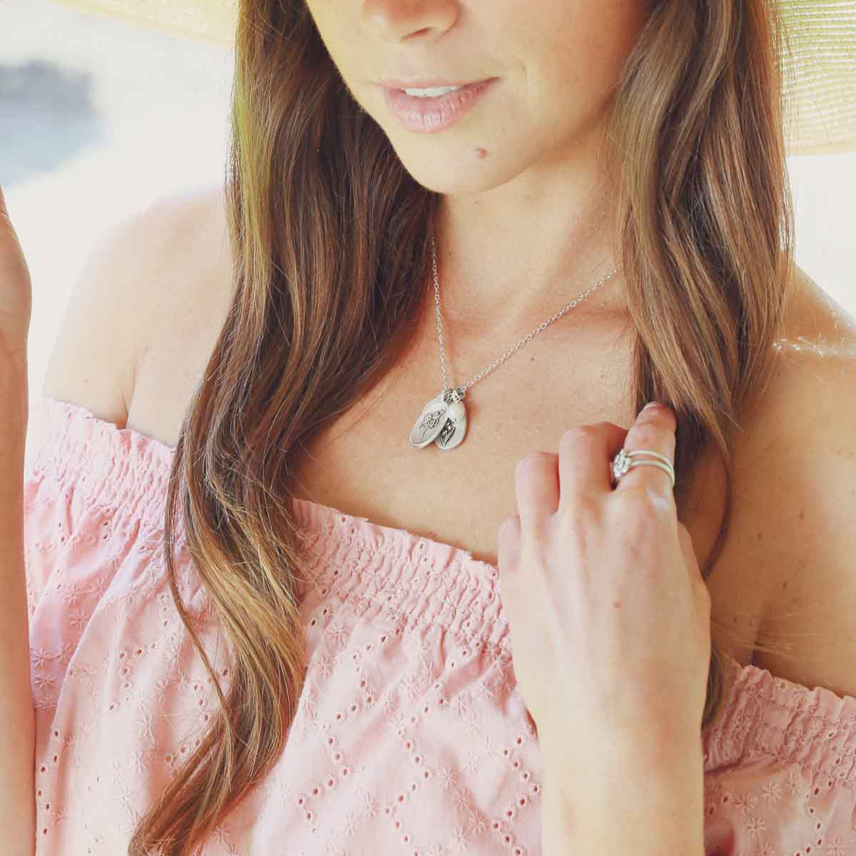 Girl wearing her April birth flower necklace handcrafted in sterling silver with a special birth month charm strung with a vintage freshwater pearl