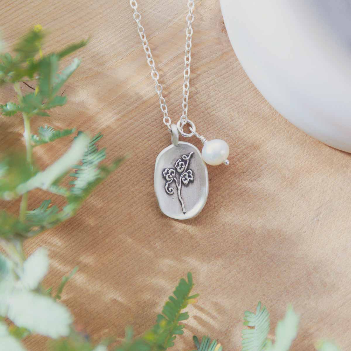 April birth flower necklace handcrafted in sterling silver with a special birth month charm strung with a vintage freshwater pearl