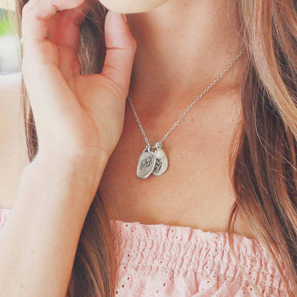 Girl wearing her April birth flower necklace handcrafted in sterling silver with a special birth month charm strung with a vintage freshwater pearl