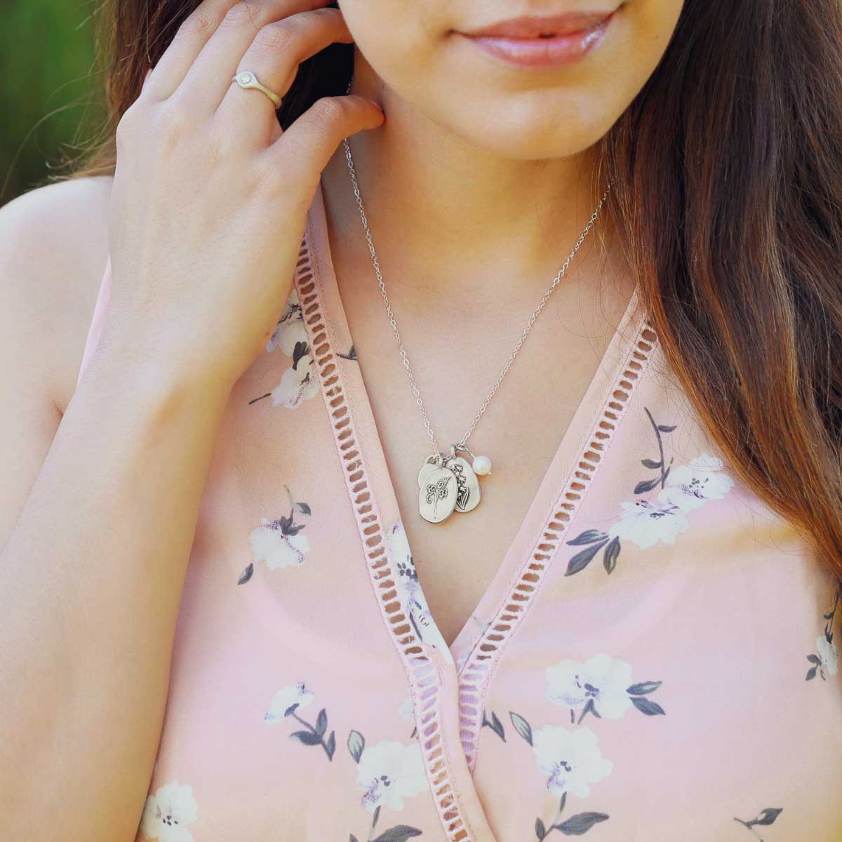 Girl wearing her April birth flower necklace handcrafted in sterling silver with a special birth month charm strung with a vintage freshwater pearl