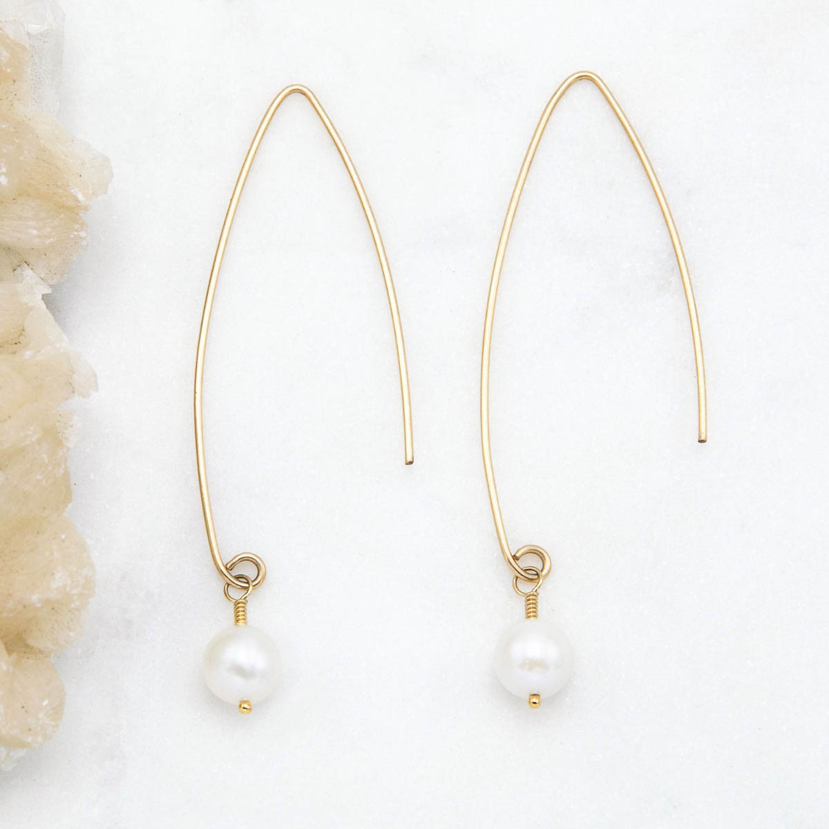 10k yellow gold artisan pearl earrings on a marble background