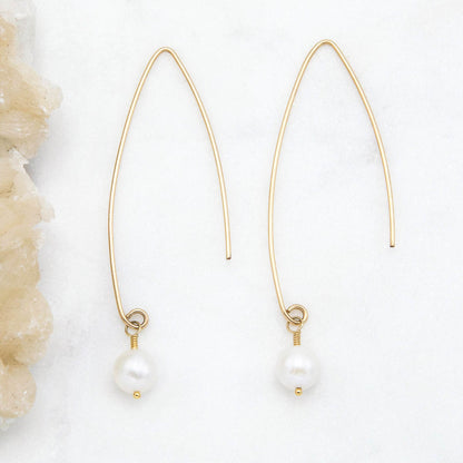 10k yellow gold artisan pearl earrings on a marble background