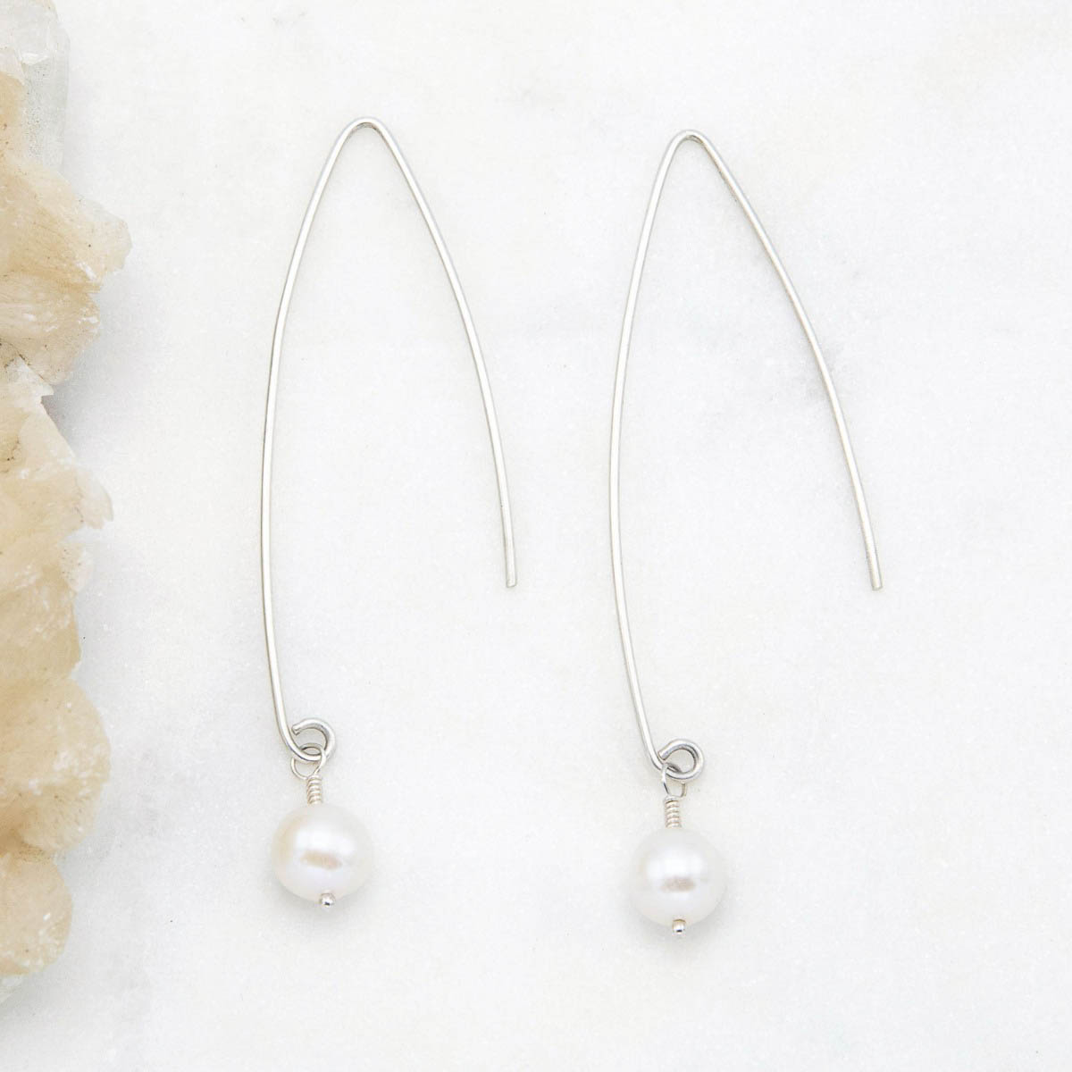 sterling silver artisan pearl earrings on marble background