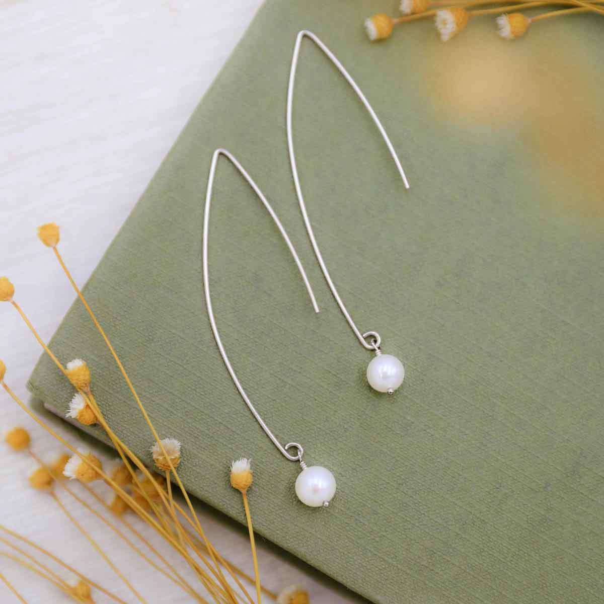 sterling silver artisan pearl earrings on a green book