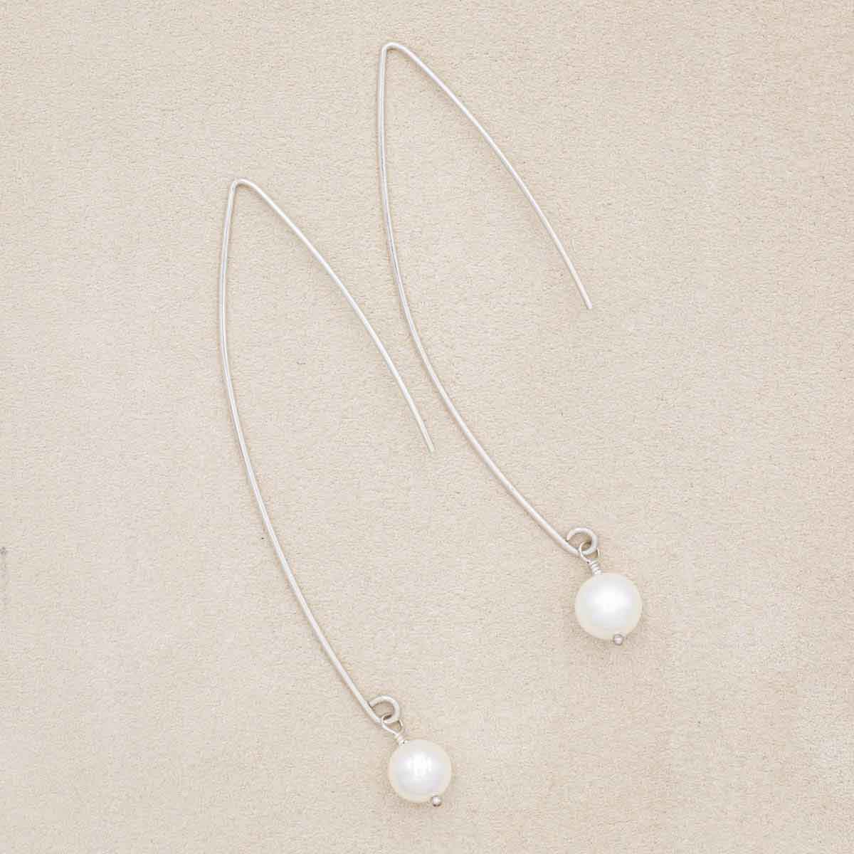 sterling silver artisan pearl earrings on marble background