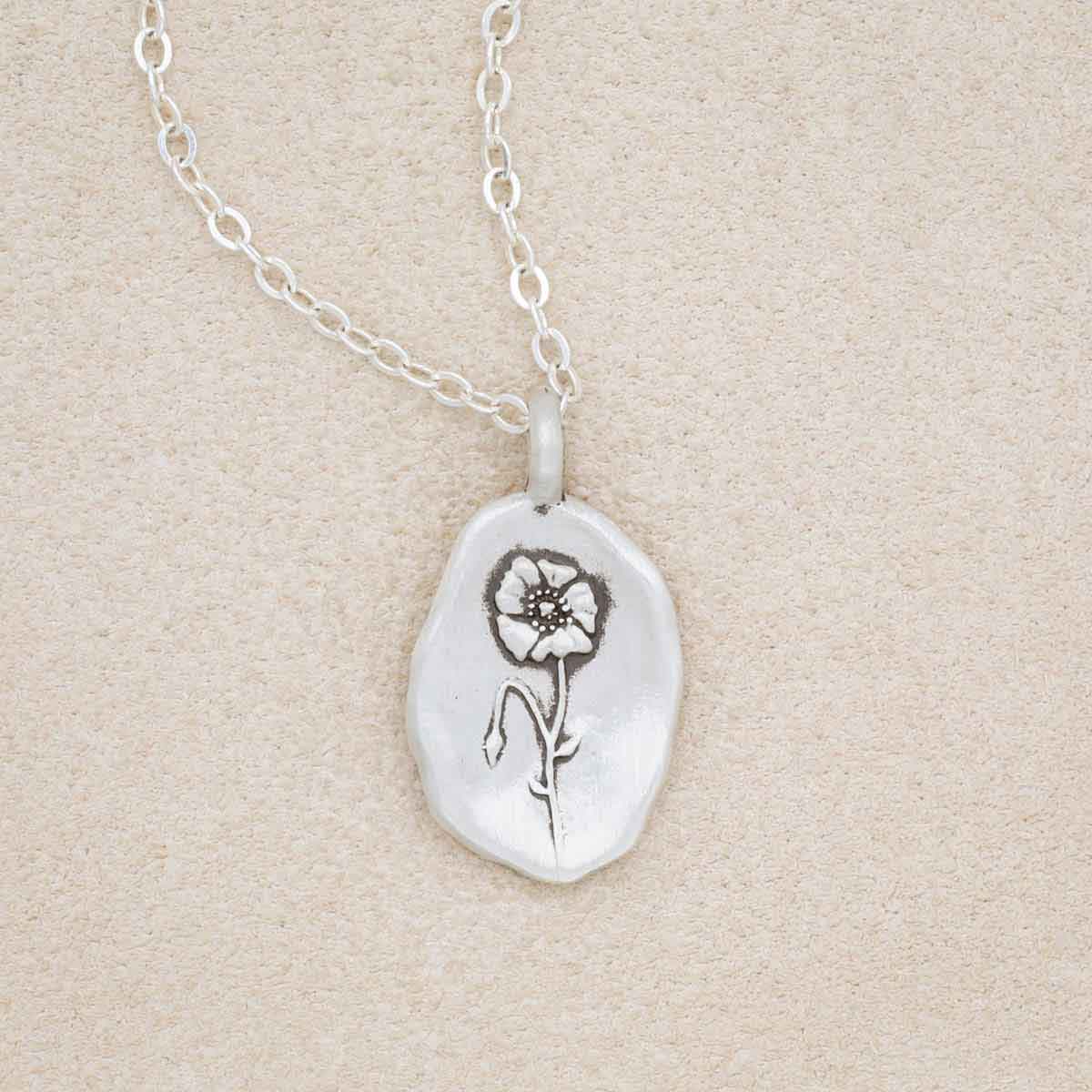 sterling silver August birth flower necklace, on beige background