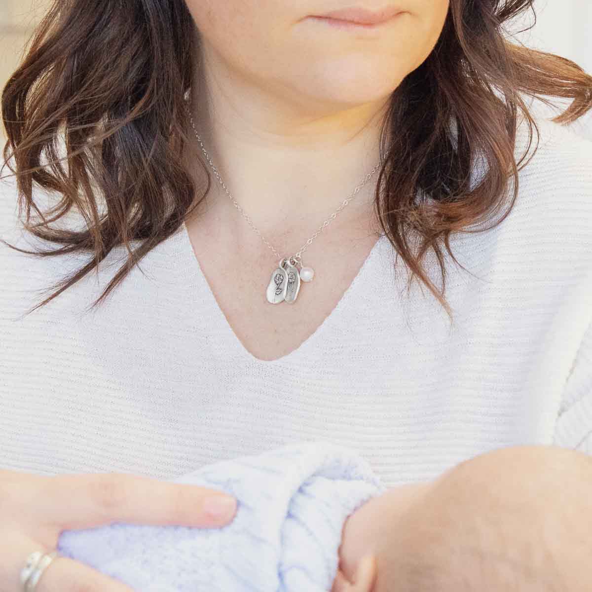 Girl wearing her August birth flower necklace handcrafted in sterling silver with a special birth month charm strung with a vintage freshwater pearl