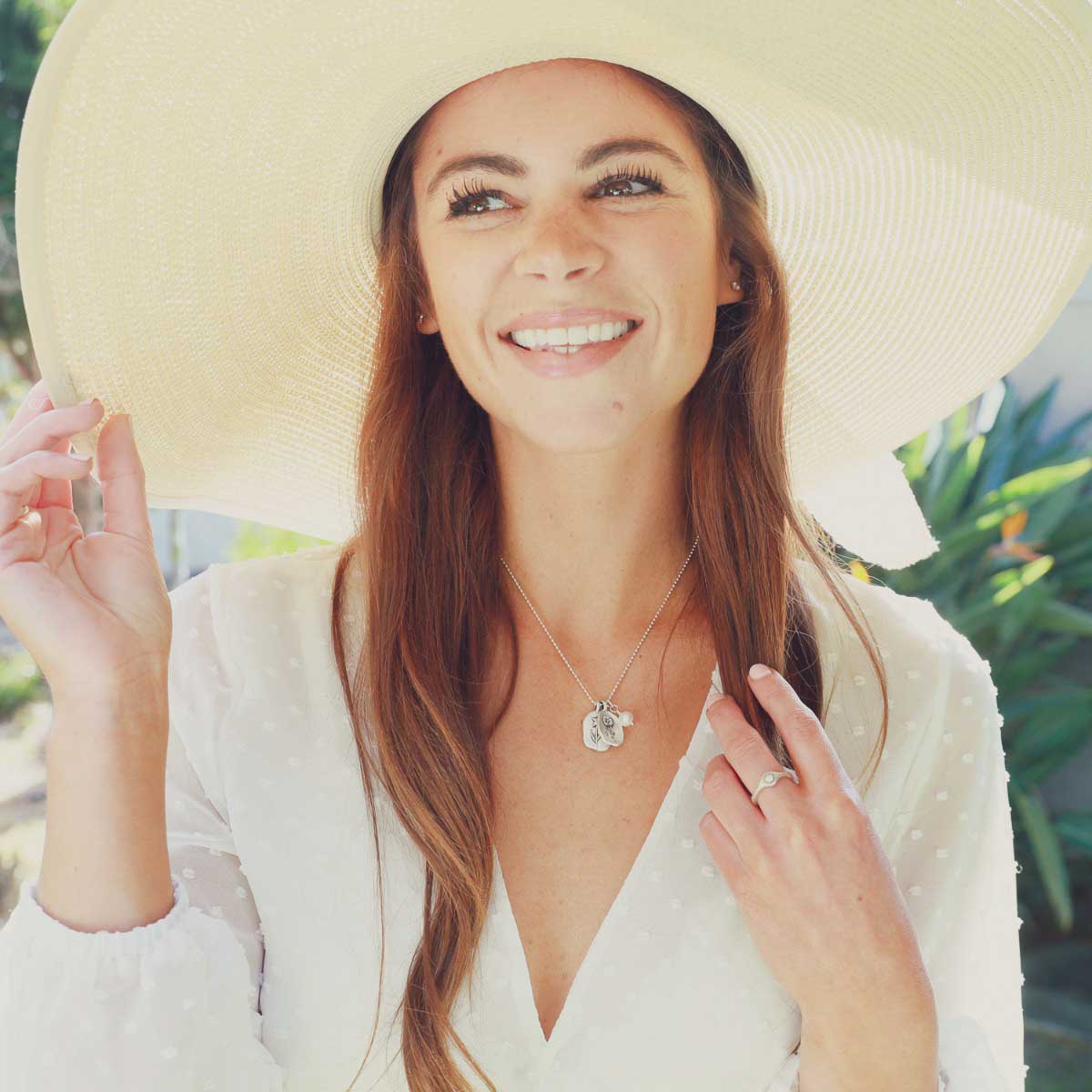 Girl wearing her August birth flower necklace handcrafted in sterling silver with a special birth month charm strung with a vintage freshwater pearl