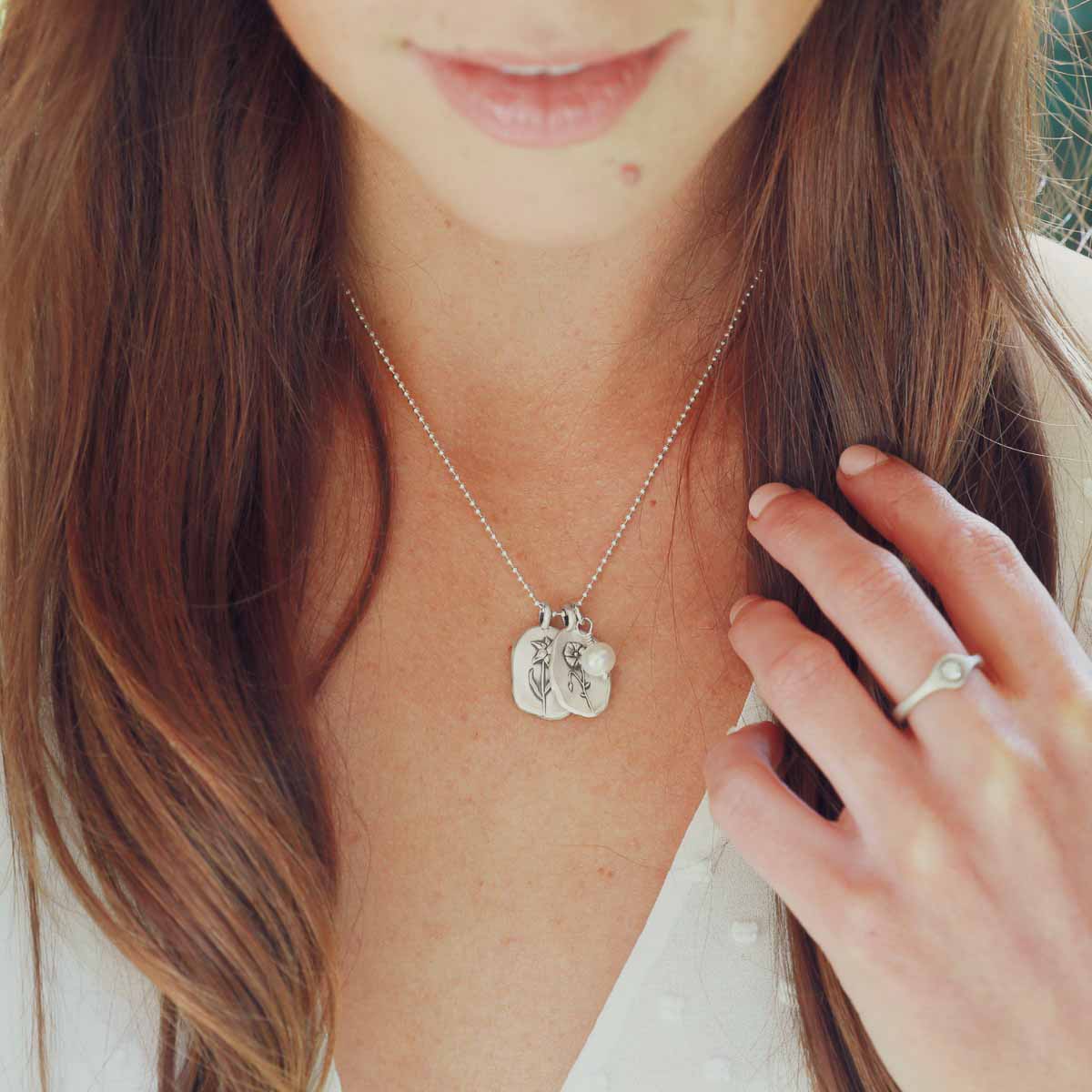 Girl wearing her August birth flower necklace handcrafted in sterling silver with a special birth month charm strung with a vintage freshwater pearl