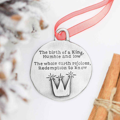 handcrafted babe in a manger pewter ornament set hung on sheer red ribbon stamped with a Christmas story poem on Christmas tree