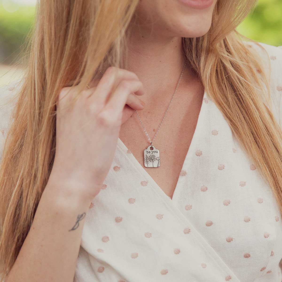 Girl wearing her Be you necklace handcrafted in pewter hung on a silver-toned link chain with the words "be you" engraved