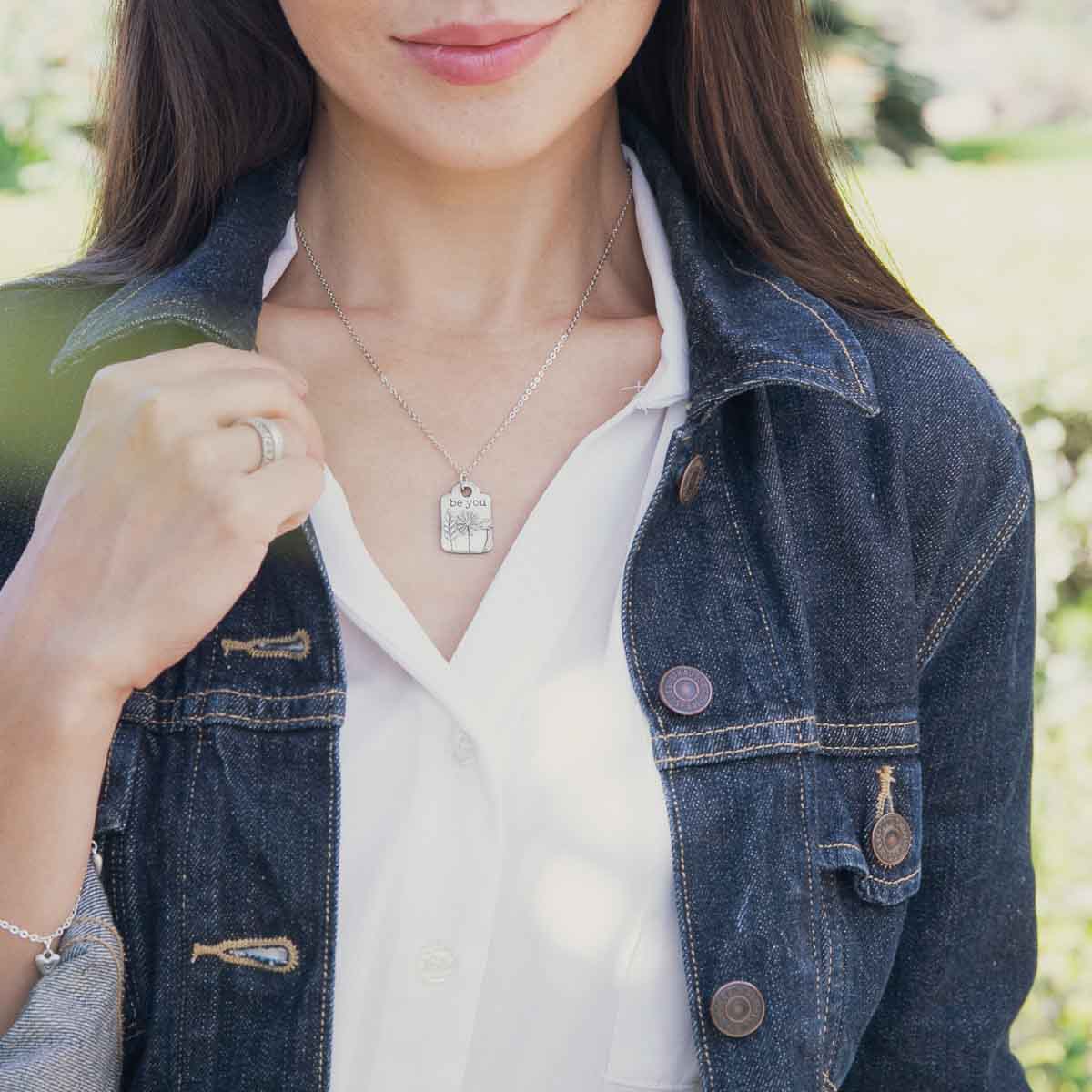 Girl wearing her Be you necklace handcrafted in pewter hung on a silver-toned link chain with the words "be you" engraved