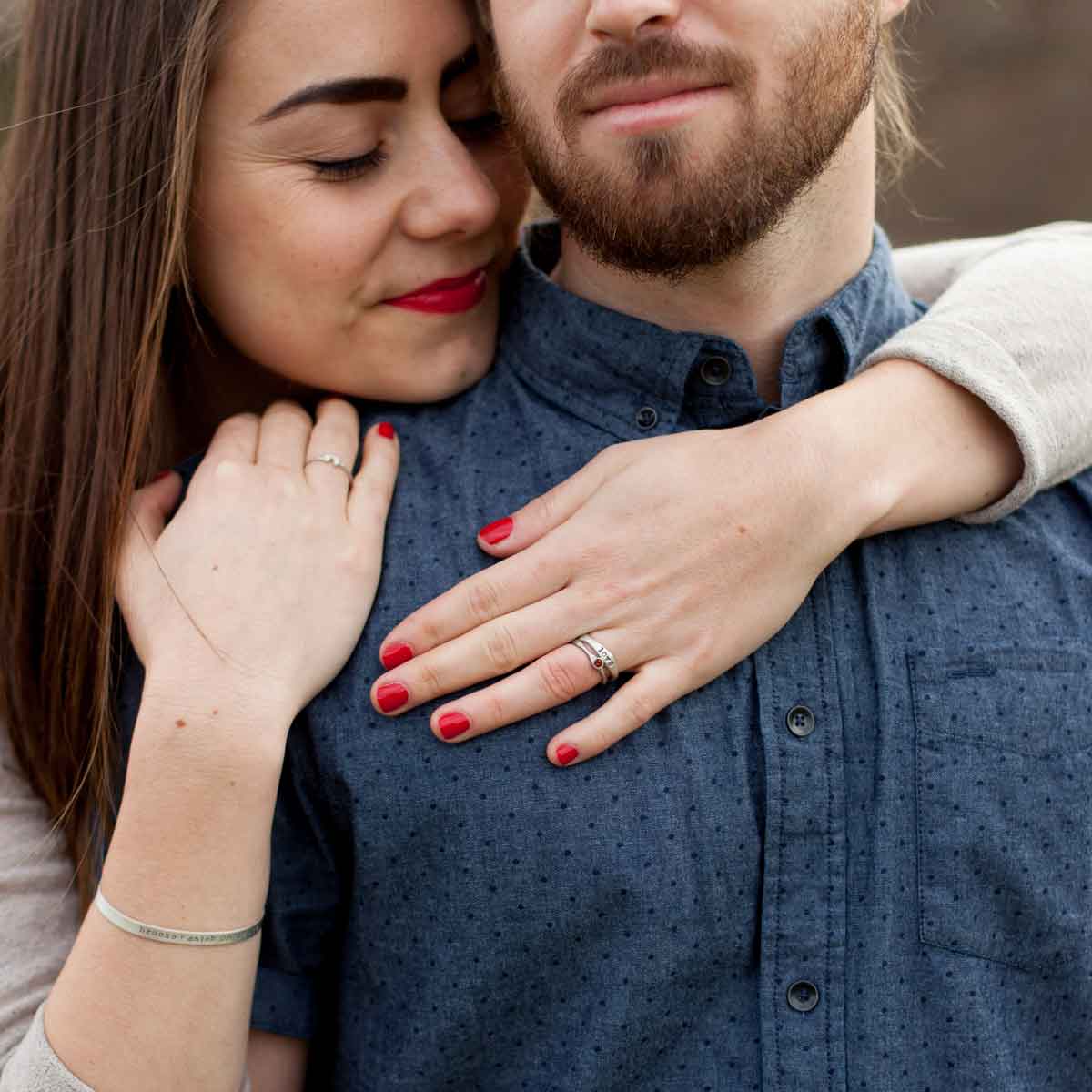 Woman wearing her bezel birthstone ring hugging her husband