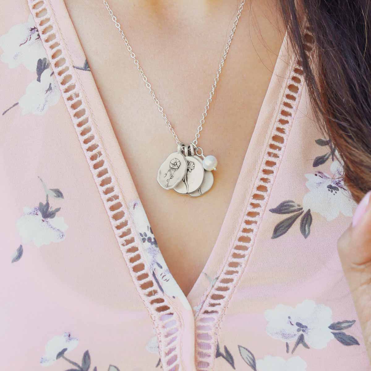 Girl wearing her birth flower charms necklace handcrafted in sterling silver with a special birth month charm strung with a vintage freshwater pearl