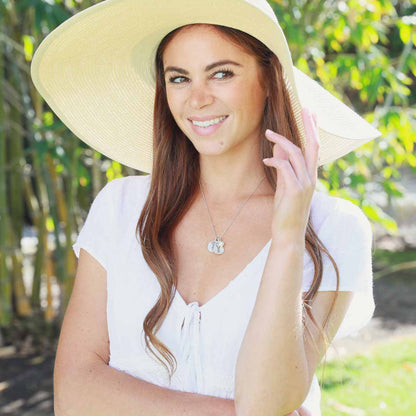 Girl wearing her birth flower charms necklace handcrafted in sterling silver with a special birth month charm strung with a vintage freshwater pearl