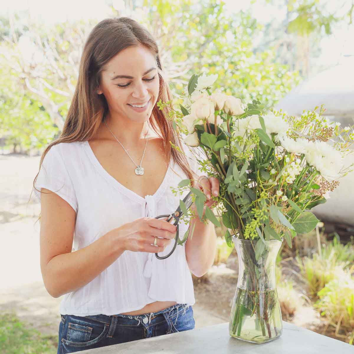 Girl wearing her birth flower charms necklace handcrafted in sterling silver with a special birth month charm strung with a vintage freshwater pearl