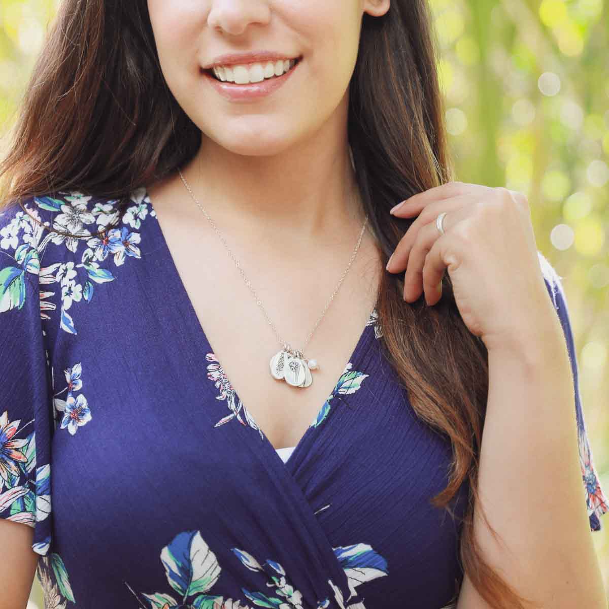 Girl wearing her birth flower charms necklace handcrafted in sterling silver with a special birth month charm strung with a vintage freshwater pearl