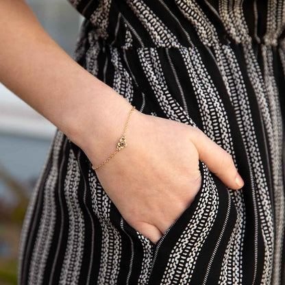 Woman wearing 10k gold birthstone bloom bracelet with sweet flower charm and 10k yellow gold lady bug charm