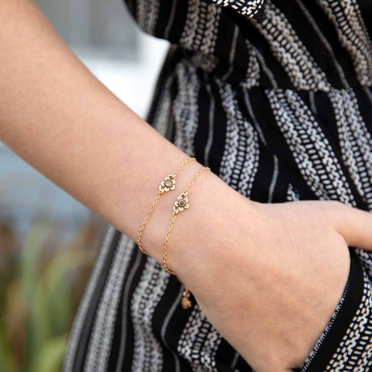 Woman wearing two10k gold birthstone bloom bracelets with sweet flower charm and 10k yellow gold lady bug charm