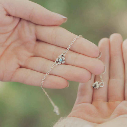 hands holding sterling silver birthstone bloom bracelet with sweet flower charm and sterling silver lady bug charm