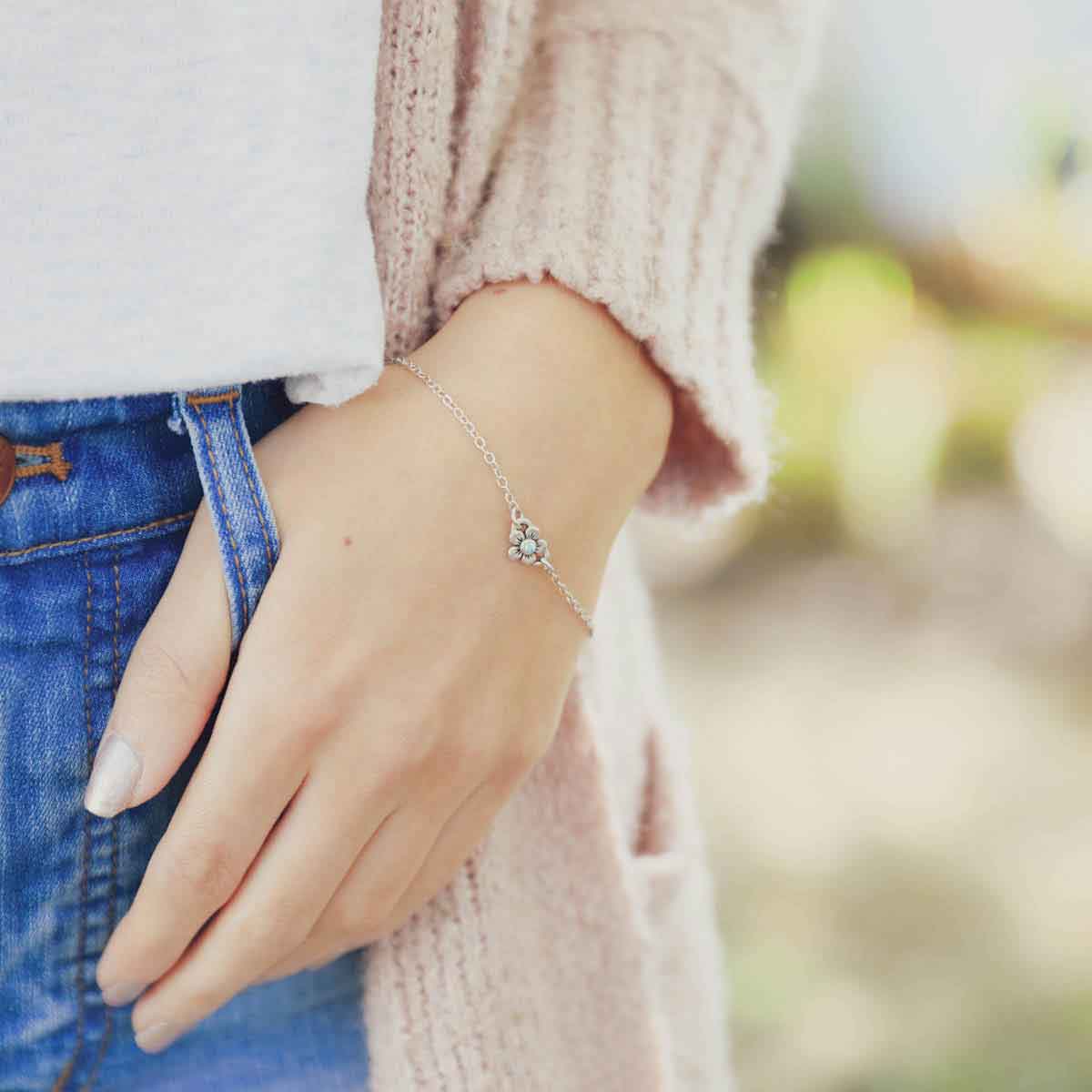 Woman wearing sterling silver birthstone bloom bracelet with sweet flower charm and sterling silver lady bug charm