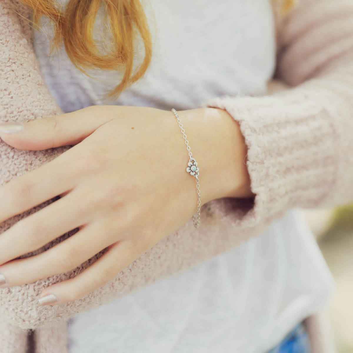 Woman wearing sterling silver birthstone bloom bracelet with sweet flower charm and sterling silver lady bug charm