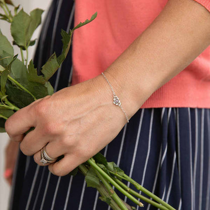 Woman wearing sterling silver birthstone bloom bracelet with sweet flower charm and sterling silver lady bug charm