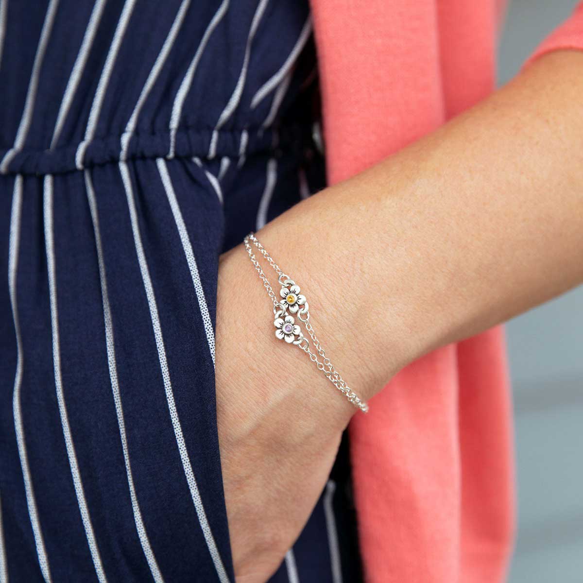 Woman wearing sterling silver birthstone bloom bracelet with sweet flower charm and sterling silver lady bug charm