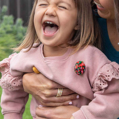 Girl wearing her Stackable birthstone rings handcrafted in 10k yellow gold with 2mm birthstones holding her daughter 