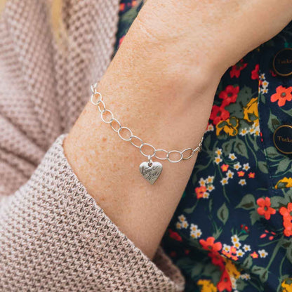 Woman wearing sterling silver Brave Love emblem bracelet with a matte brushed finish