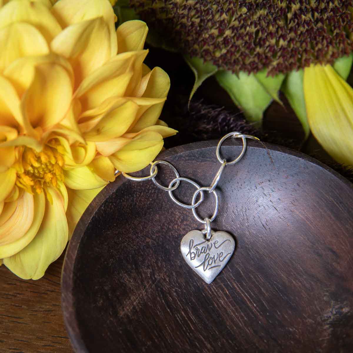 Sterling silver Brave Love emblem bracelet with a matte brushed finish on display