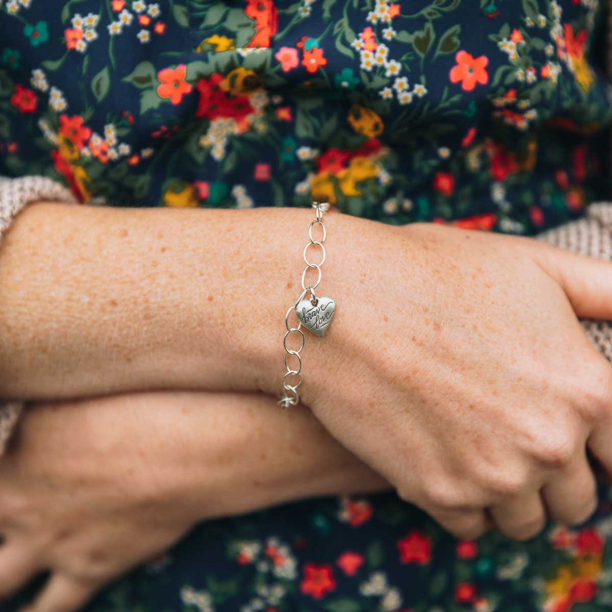 Woman wearing her handcrafted sterling silver Brave Love emblem bracelet with a matte brushed finish