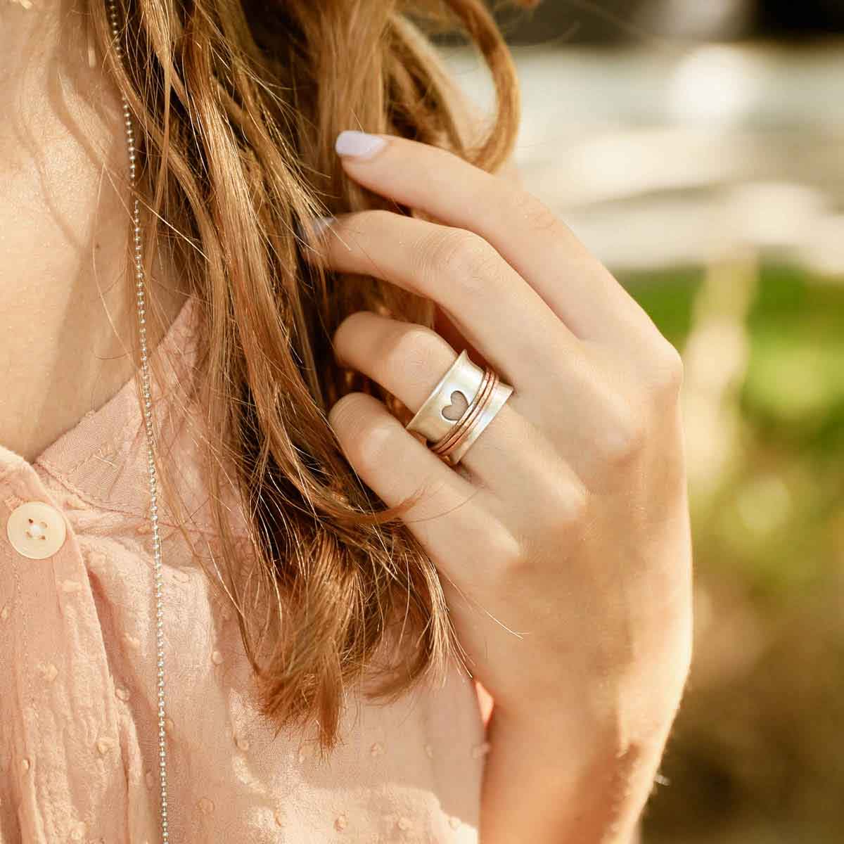 close up of brave love® spinner ring {sterling silver & bronze} on girl's hand