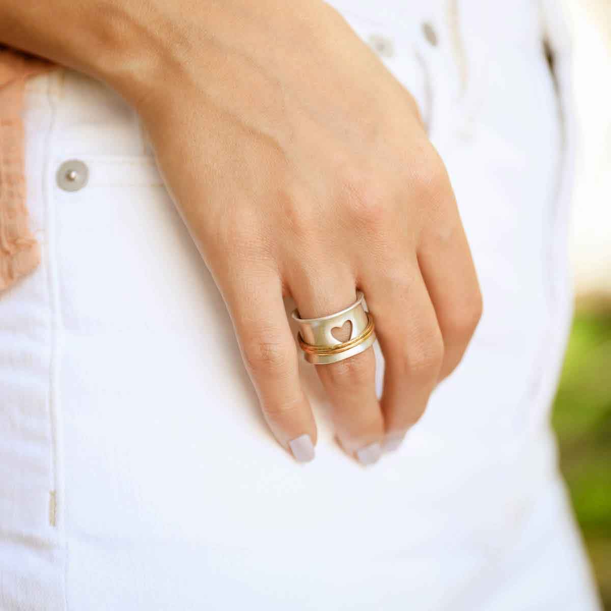 close up of girl wearing brave love® spinner ring {sterling silver & 10k gold} with thumb in pant pocket