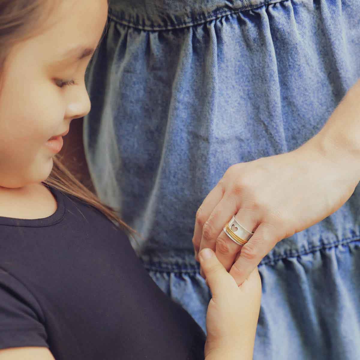 daughter holding mom's hand wearing brave love spinner ring {sterling silver & 10k gold}