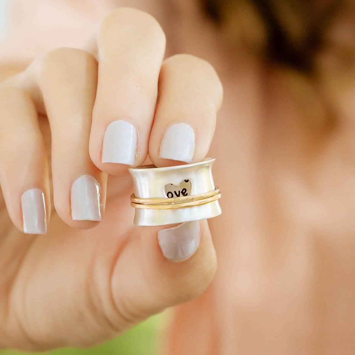 close up of girl holding brave love® spinner ring {sterling silver & 10k gold}