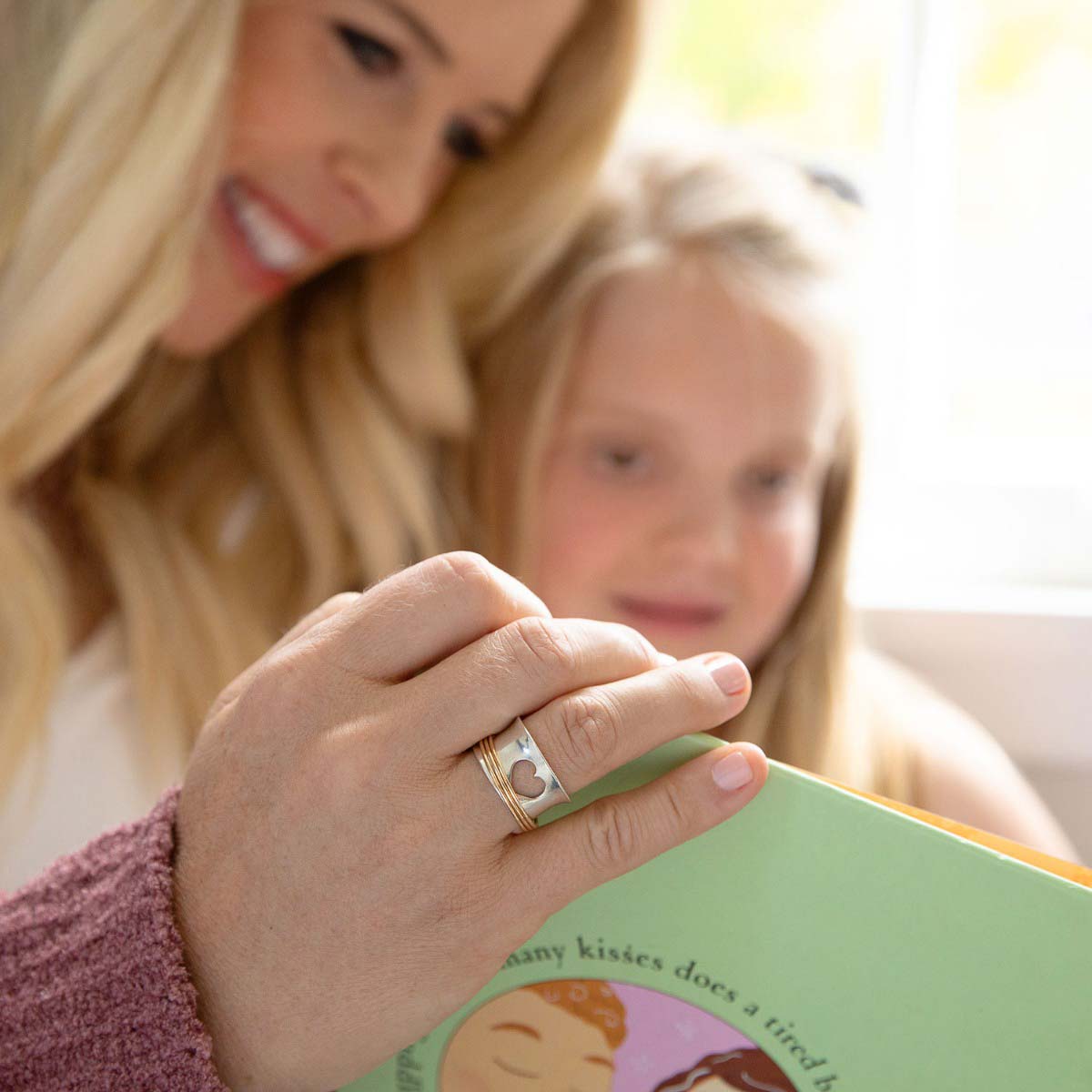 Woman wearing Brave Love spinner ring with a sterling silver band and gold-filled spinners and engraved with "brave love" on the inside with her daughter