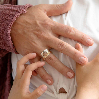 Woman wearing Brave Love spinner ring with a sterling silver band and gold-filled spinners and engraved with "brave love" on the inside