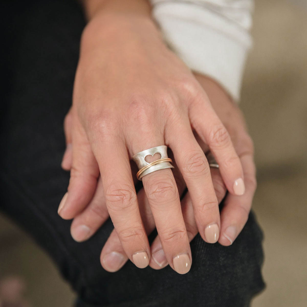 Woman wearing Brave Love spinner ring with a sterling silver band and gold-filled spinners and engraved with "brave love" on the inside