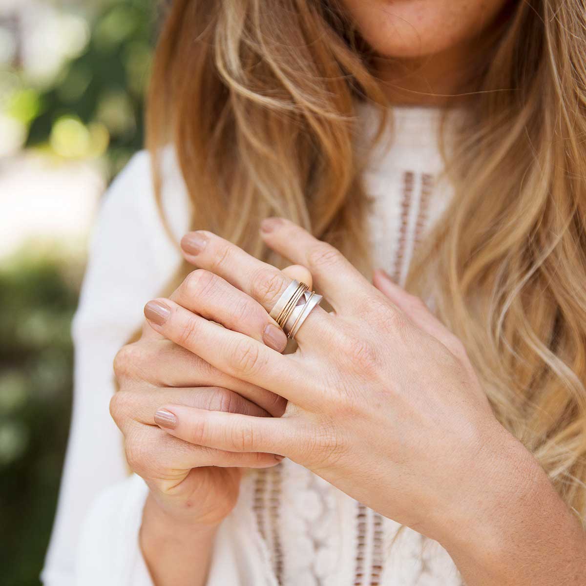 Woman wearing Brave Love spinner ring with a sterling silver band and gold-filled spinners and engraved with "brave love" on the inside