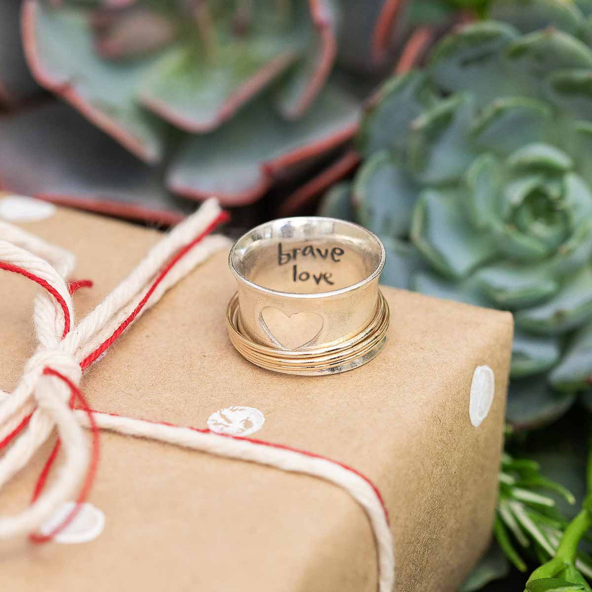 Brave Love spinner ring with a sterling silver band and gold-filled spinners and engraved with "brave love" on the inside