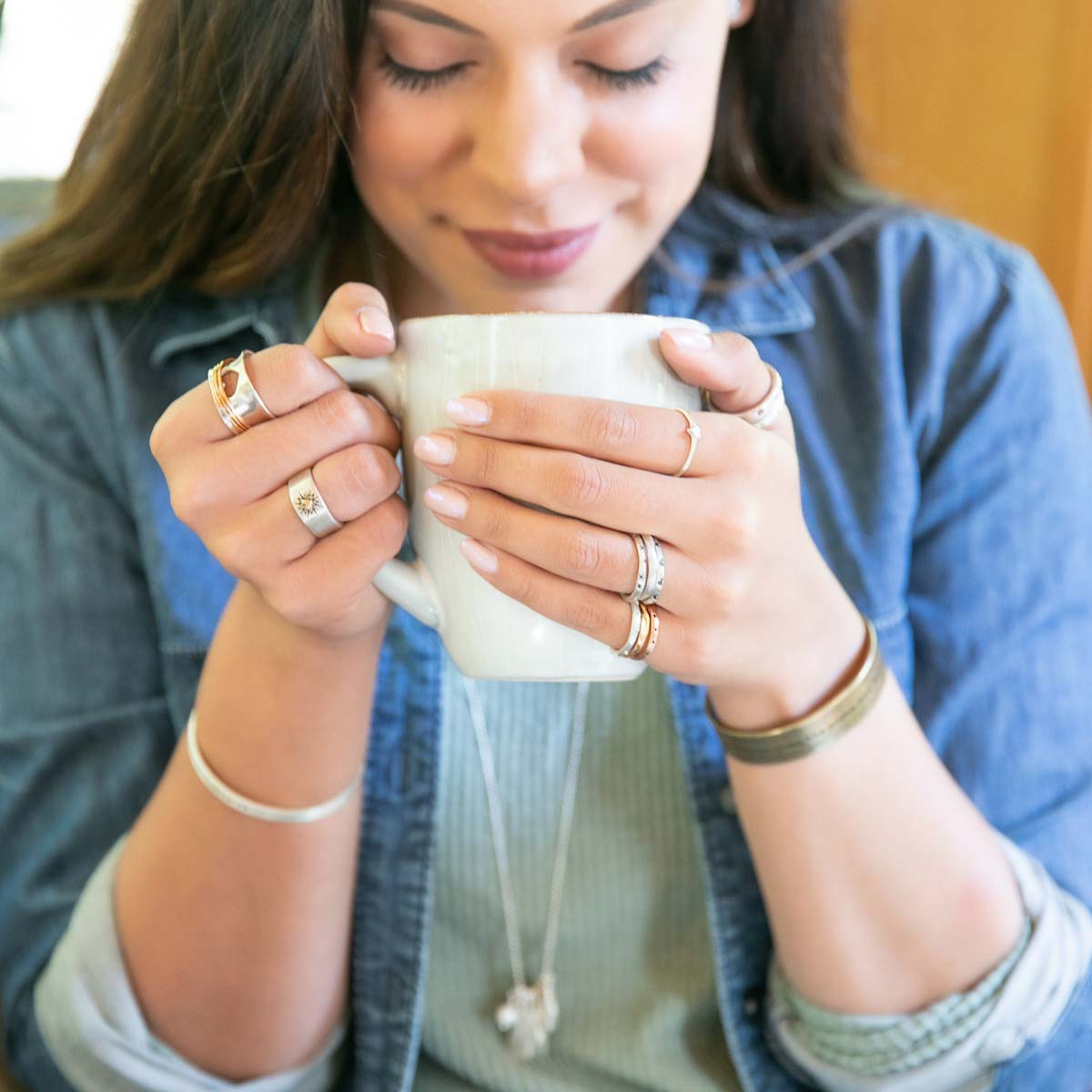 Woman wearing Brave Love spinner ring with a sterling silver band and gold-filled spinners and engraved with "brave love" on the inside along with other jewelry