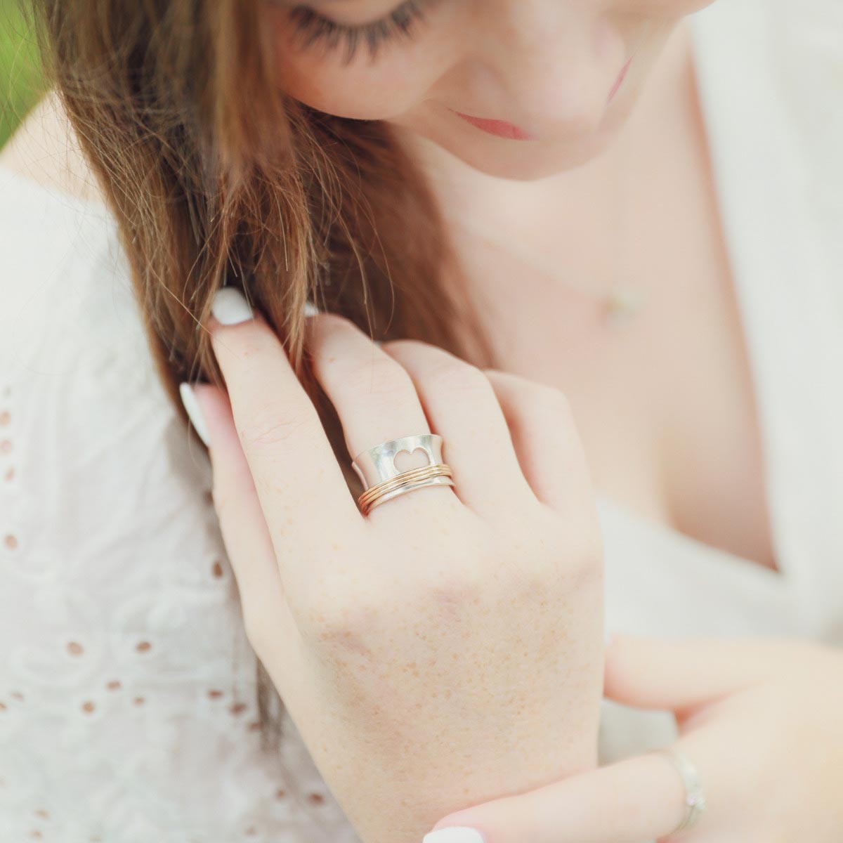 Woman wearing Brave Love spinner ring with a sterling silver band and gold-filled spinners and engraved with "brave love" on the inside