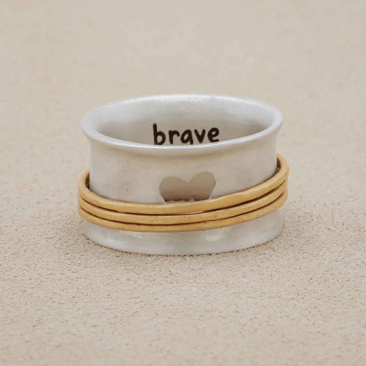 brave love® spinner ring {sterling silver & 10k gold} on white marble background