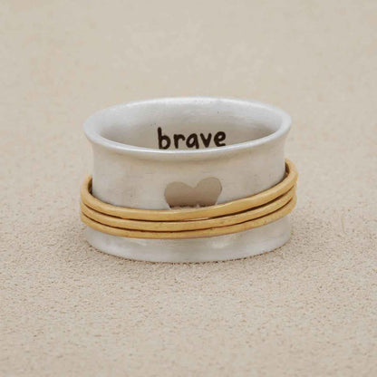 brave love® spinner ring {sterling silver & 10k gold} on white marble background