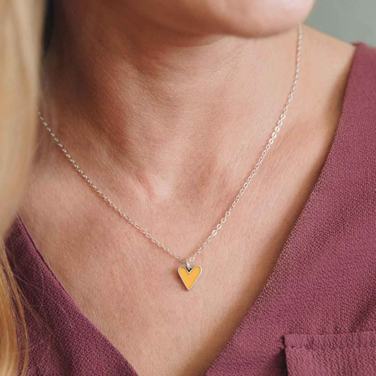 Girl wearing her Brave Love tiny heart necklace handcrafted in sterling silver with choice of color epoxy