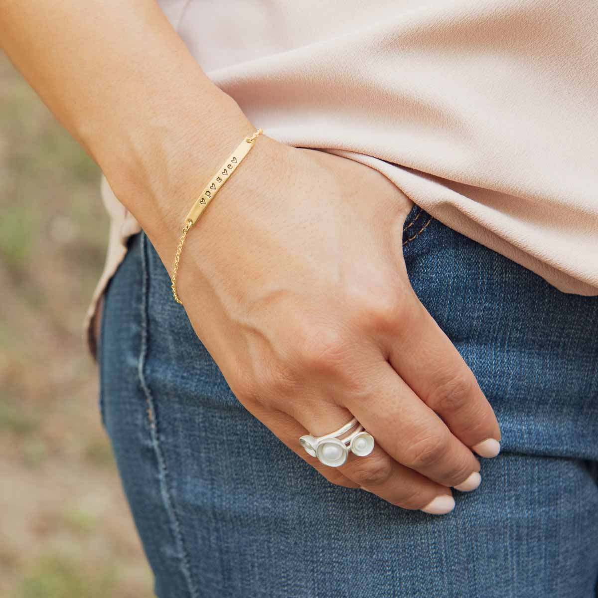 Woman wearing her handcrafted carry my heart 10k yellow gold bracelet with aventurine stone