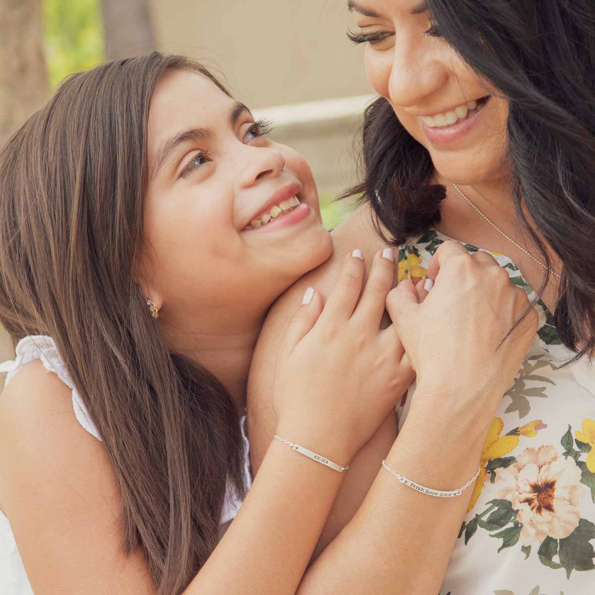 Friends holding hands while both wearing a personalized sterling silver carry my heart bracelet